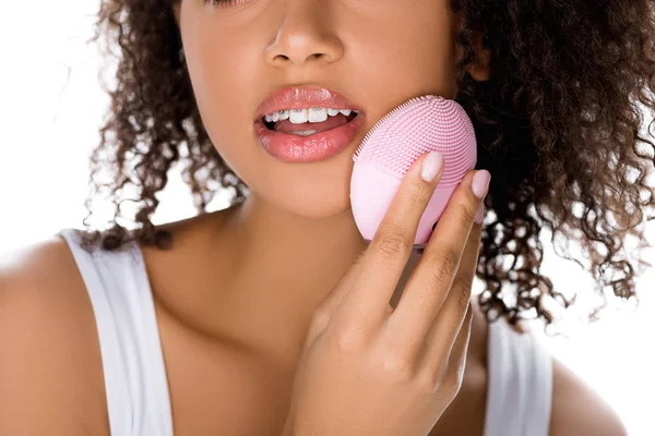 Vue recadrée de fille afro-américaine avec les yeux fermés à l'aide de silicone nettoyage brosse faciale, isolé sur blanc — Photo de stock