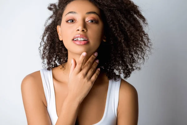 Atractiva chica afroamericana morena con frenos dentales, aislada en gris - foto de stock