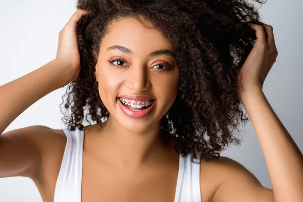 Bela menina afro-americana positiva com aparelho dentário, isolado em cinza — Fotografia de Stock