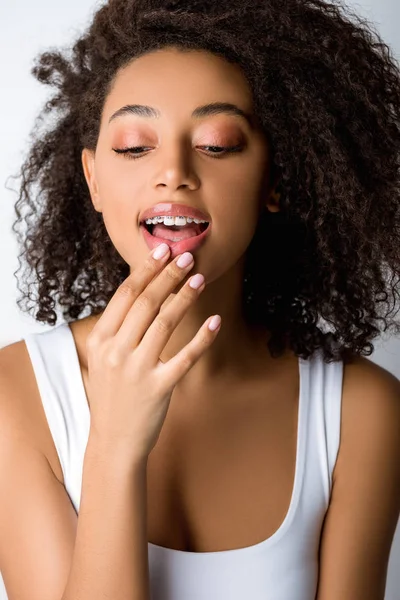 Curly smiling african american girl with dental braces, isolated on grey — Stock Photo