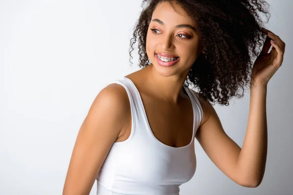 Happy curly african american girl with dental braces, isolated on grey — Stock Photo
