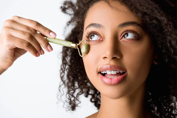 Sorridente ragazza afro-americana con apparecchio dentale utilizzando uno strumento di massaggio naturale, isolato su grigio — Foto stock