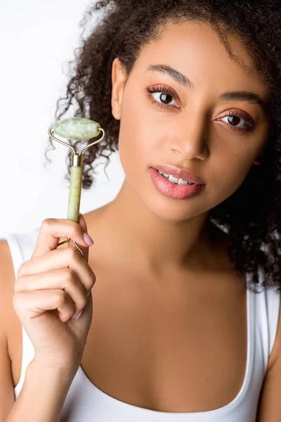 Bella ragazza afro-americana in possesso di giada rullo facciale, isolato su grigio — Foto stock