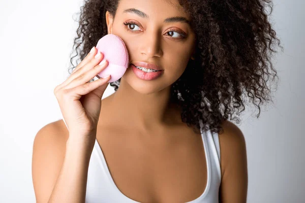 Afro-américaine fille à l'aide de silicone nettoyage brosse faciale, isolé sur gris — Photo de stock