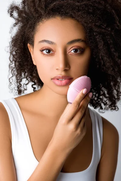 Atractiva chica afroamericana usando cepillo facial limpiador de silicona, aislado en gris - foto de stock