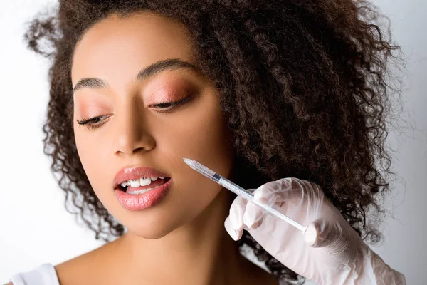 Hermosa joven afroamericana mujer haciendo inyección de belleza, aislado en gris - foto de stock