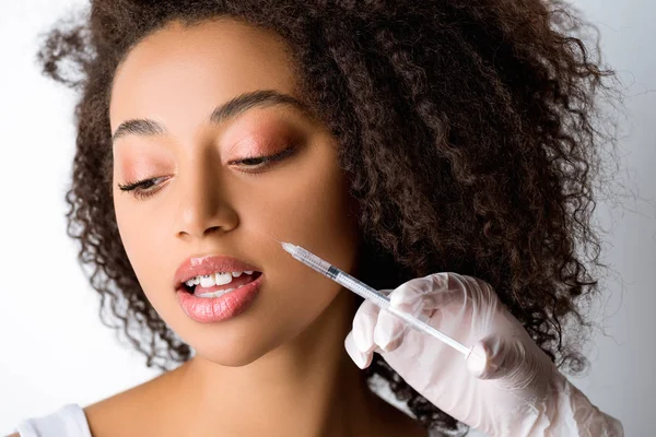 Bella giovane donna afro-americana che fa iniezione di bellezza, isolata sul grigio — Foto stock