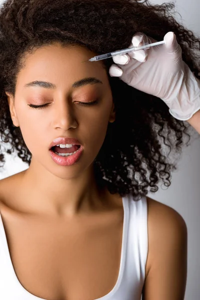 Jeune femme afro-américaine faisant injection de beauté avec douleur, isolée sur gris — Photo de stock