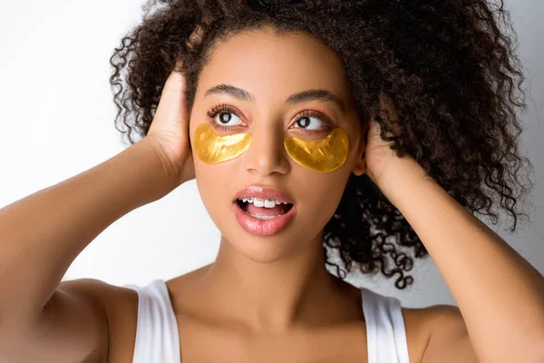 Impactado chica afroamericana con parches de ojo dorado, aislado en gris - foto de stock