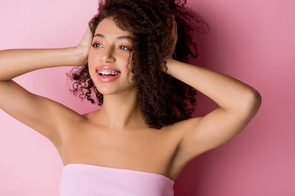 Bela menina afro-americana positiva com aparelho dentário em rosa — Fotografia de Stock