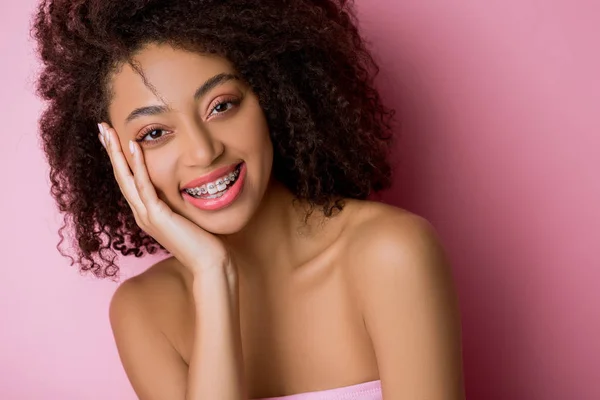 Bella felice ragazza africana americana con bretelle dentali su rosa — Foto stock