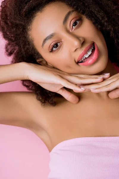 Bella sorridente ragazza afroamericana con apparecchio dentale, isolato su rosa — Foto stock