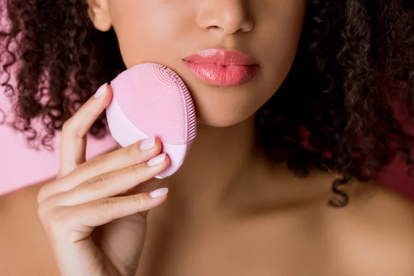 Vista recortada de mujer afroamericana usando herramienta de limpieza profunda rosa, aislado en rosa — Stock Photo