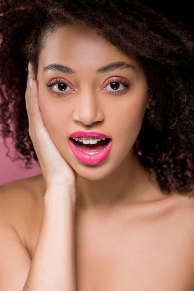 Sorpreso ragazza africana americana nuda con bretelle dentali, isolato su rosa — Foto stock