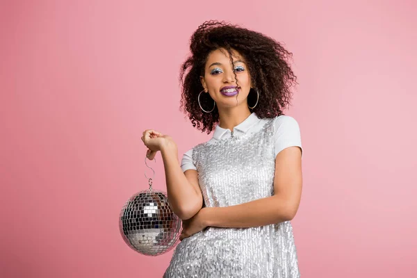 Happy emotional african american girl in paillettes dress holding disco ball, isolated on pink — Stock Photo