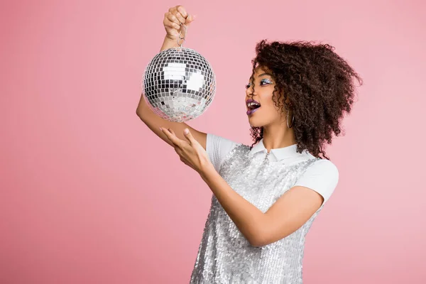 Emocionado afroamericano chica en paillettes vestido celebración disco bola, aislado en rosa - foto de stock