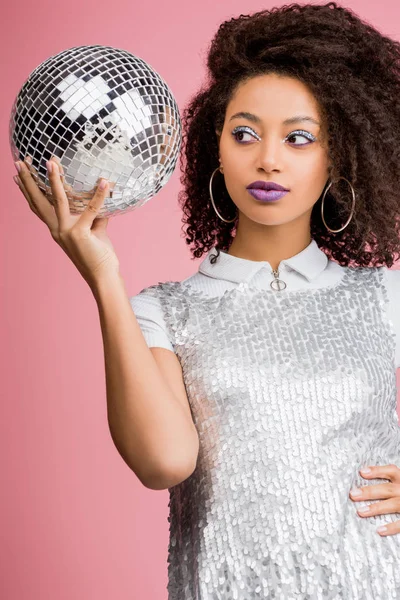Beautiful african american girl in paillettes dress holding disco ball, isolated on pink — Stock Photo