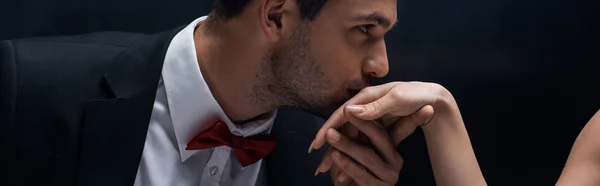 Panoramaaufnahme eines schönen Mannes, der die Hand einer Frau küsst, isoliert auf schwarz — Stockfoto