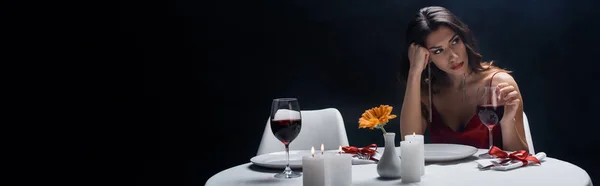 Tiro panorâmico de mulher chata olhando para a mesa servida isolado em preto — Fotografia de Stock