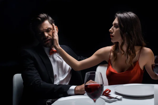 Schöne Frau ohrfeigt Mann bei romantischem Abendessen isoliert auf schwarz — Stockfoto