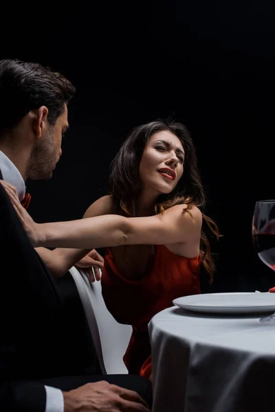 Elegancia pareja peleando durante la cena romántica aislado en negro - foto de stock