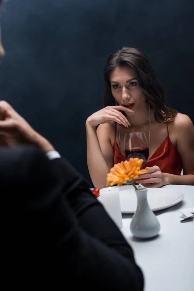 Enfoque selectivo de la hermosa mujer mirando al novio en la mesa servida sobre fondo negro con humo - foto de stock