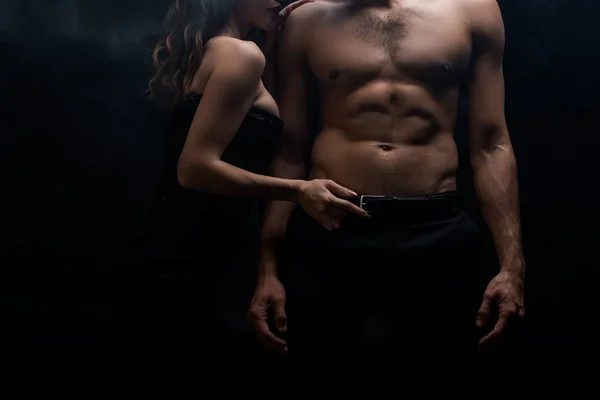 Cropped view of woman touching belt of shirtless boyfriend isolated on black — Stock Photo