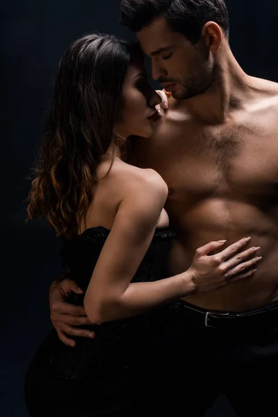 Handsome shirtless man hugging attractive girlfriend isolated on black — Stock Photo