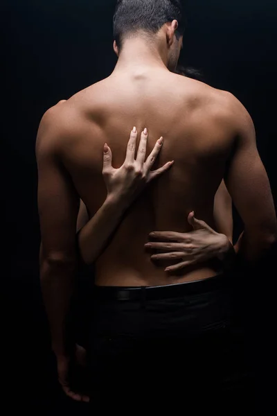 Woman hands touching muscular back of boyfriend isolated on black — Stock Photo