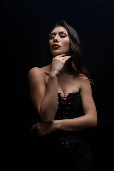 Sensuale donna con la mano dal mento distogliendo lo sguardo isolato sul nero — Foto stock