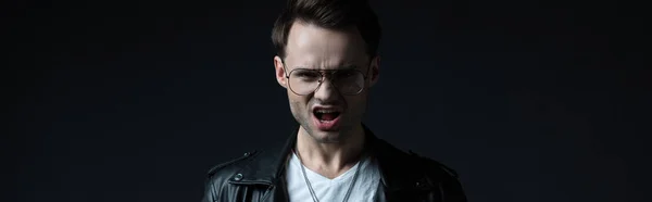 Stylish brutal man in biker jacket screaming isolated on black, panoramic shot — Stock Photo