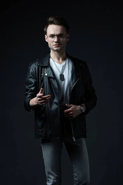 Stylish brutal man in biker jacket gesturing isolated on black — Stock Photo