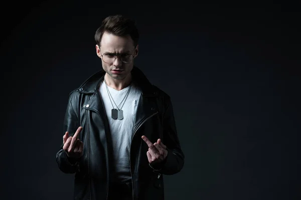 Stylish brutal man in biker jacket showing middle fingers isolated on black — Stock Photo