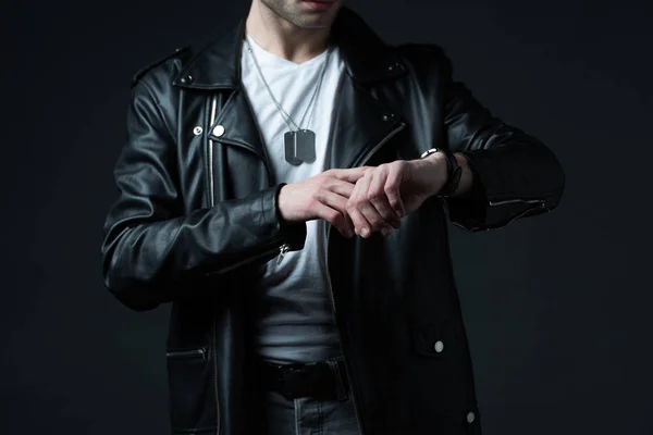 Cropped view of stylish brutal man in biker jacket with wristwatch isolated on black — Stock Photo