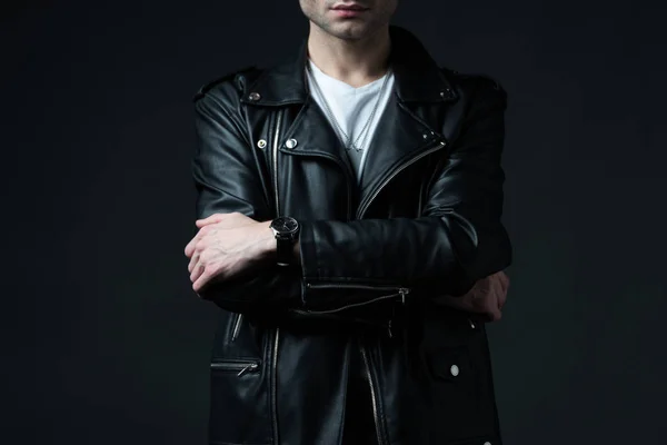 Cropped view of stylish brutal man in biker jacket with crossed arms isolated on black — Stock Photo