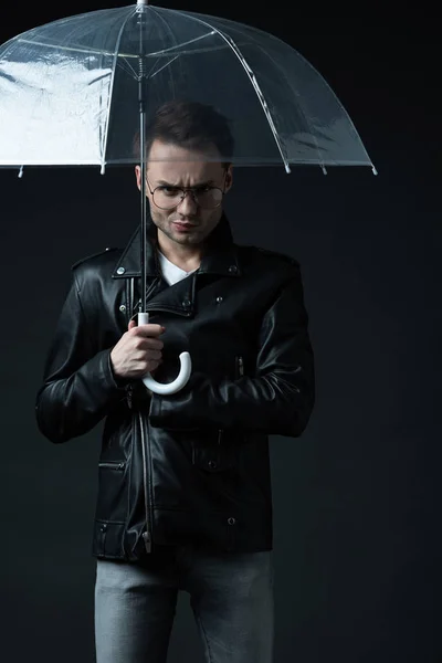 Angry stylish brutal man in biker jacket with umbrella isolated on black — Stock Photo