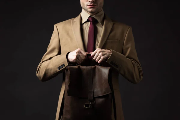 Cropped view of elegant man in beige suit holding brown leather backpack isolated on black — Stock Photo