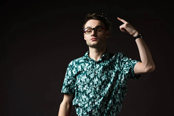 Confident fashionable man in eyeglasses pointing with finger at crown isolated on black — Stock Photo