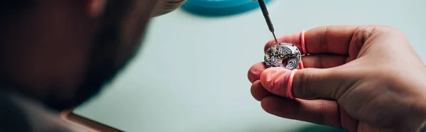 Panoramic shot of watchmaker in latex fingertips setting wristwatch detail with screwdriver — Stock Photo