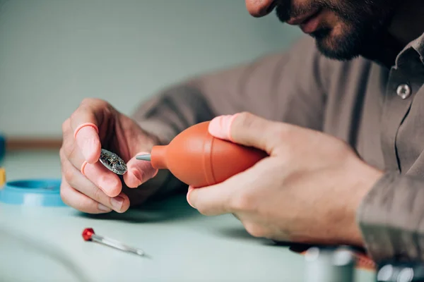 Ausgeschnittene Ansicht des Uhrmachers, der Uhrendetail mit Gebläse reinigt — Stockfoto