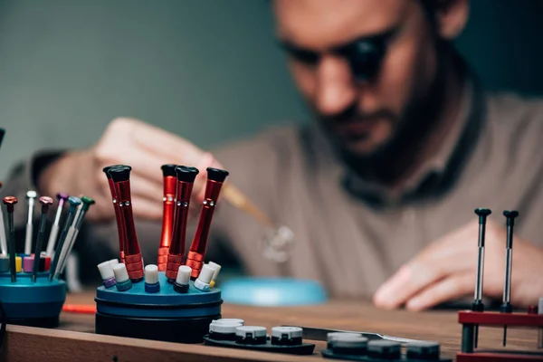 Enfoque selectivo de destornilladores y equipos con relojero de trabajo en la mesa - foto de stock