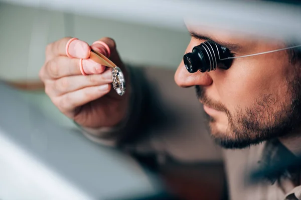 Vue latérale du bel horloger en loupe de lunettes regardant la partie montre-bracelet — Photo de stock