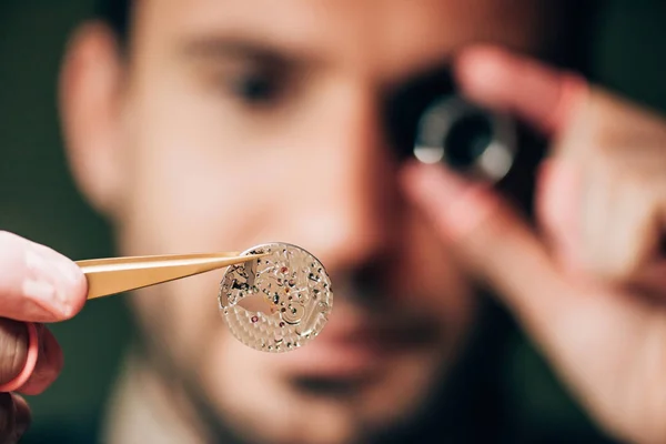 Selective focus of clockmaker holding watch part in tweezers — Stock Photo