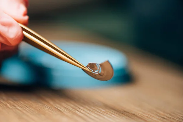 Cropped view of clockmaker holding in tweezers watch part at table — Stock Photo