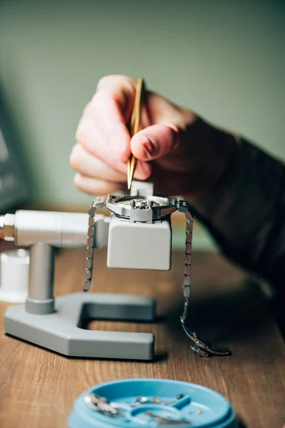 Ausgeschnittene Ansicht eines Uhrmachers, der Armbanduhren per Werkzeugablage auf dem Tisch repariert — Stockfoto