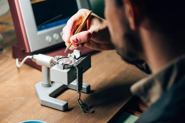 Selective focus of clockmaker working with wristwatch and watch tester at table — Stock Photo