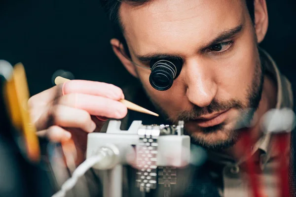 Selektiver Fokus des Uhrmachers, der mit Armbanduhr am Uhrwerkhalter arbeitet, isoliert auf schwarz — Stockfoto