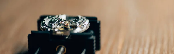 Vista de cerca del reloj de pulsera mecánico en el soporte de movimiento en la mesa de madera, tiro panorámico - foto de stock