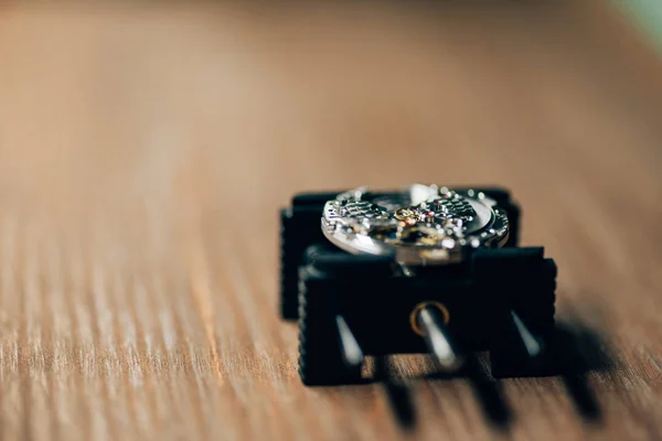 Foco selectivo del soporte de movimiento con reloj de pulsera en mesa de madera - foto de stock