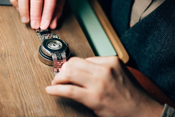 Vista ritagliata dell'orologiaio con supporto per orologio da polso sul tavolo — Stock Photo